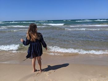 Rear view of woman on beach against sky