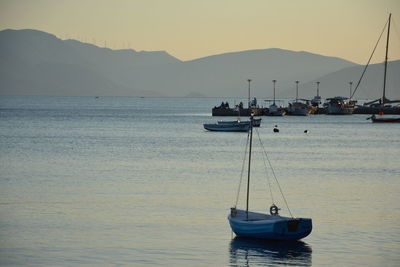 Sailboats sailing in sea against sky during sunset
