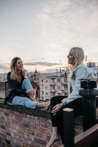 Woman smiling while sitting outdoors against sky