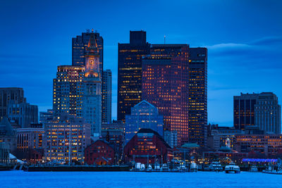 Illuminated buildings in city against sky during winter