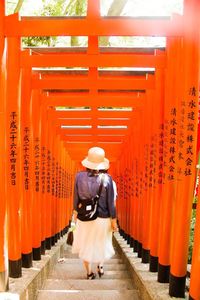 Rear view of woman walking through torii gates at hie shrine