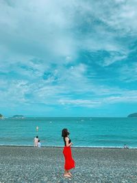 Rear view of women standing at beach against sky