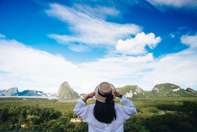 Rear view of woman with umbrella against sky