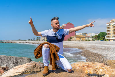 Full length of man with arms raised against sky