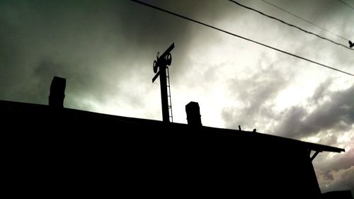 Low angle view of silhouette building against cloudy sky