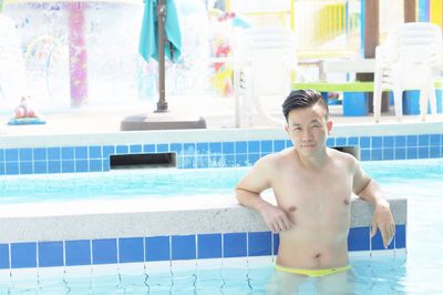 Portrait of shirtless man standing in swimming pool