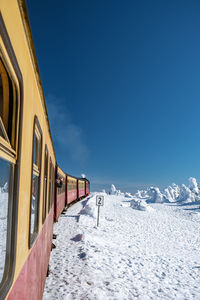 Train on snow covered landscape against blue sky