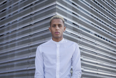 Portrait of young man standing against wall