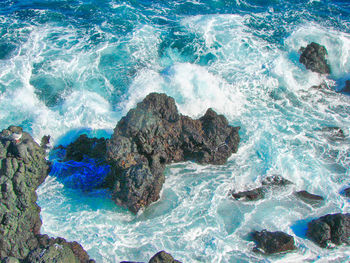 High angle view of waves breaking on rocks