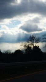 Road passing through landscape against cloudy sky