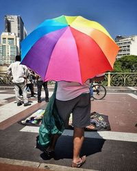 Rear view of people with umbrella standing in rain