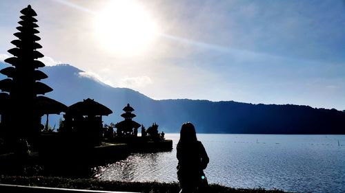 Silhouette people by lake against sky