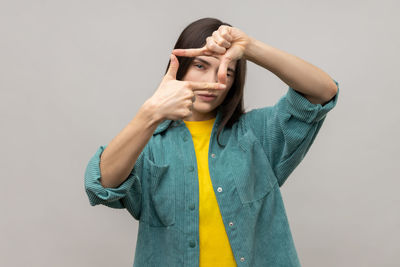 Portrait of young woman standing against white background