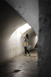 Side view of young woman standing against wall