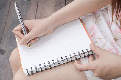 Midsection of woman writing in book at home