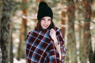 Portrait of smiling young woman holding snow in forest