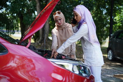 Couple standing by car on road