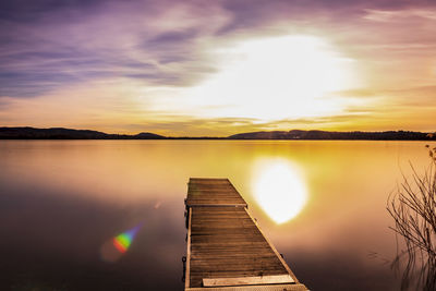 Pier over lake against sky during sunset