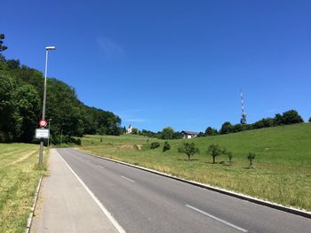 Road by street against clear blue sky