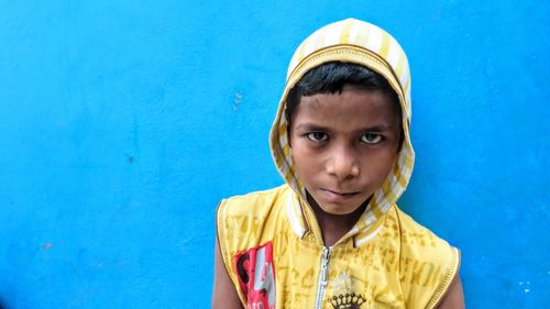 Portrait of teenage boy against blue wall
