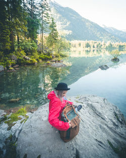 Woman sitting on rock by lake