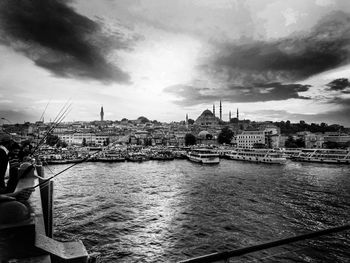 View of buildings by river against cloudy sky