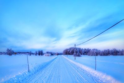 Snow covered landscape against blue sky