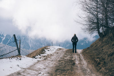 Rear view of woman walking on road during winter