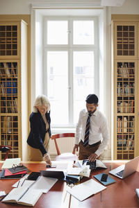 Senior lawyer with male coworker researching in library