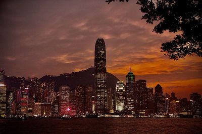 Illuminated buildings against cloudy sky during sunset