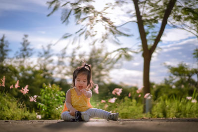 Cute boy sitting on plant against trees