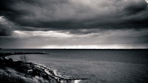 Scenic view of beach against cloudy sky