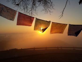 Low angle view of flags hanging against sky during sunset