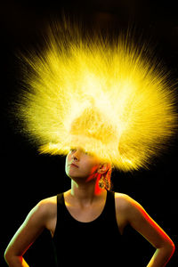 Boy looking away while standing against black background