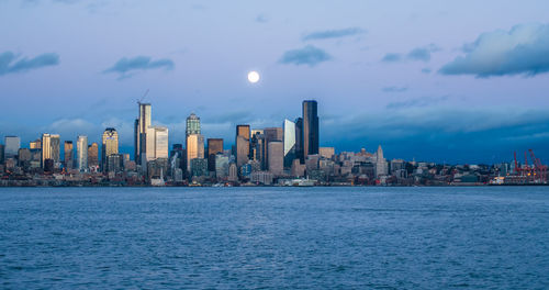 A full moon shines above the seattle skyline.