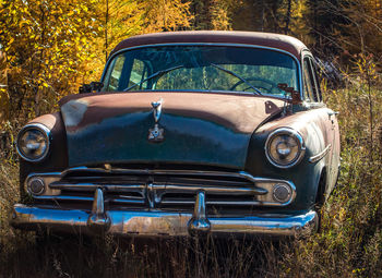 Abandoned vintage car on grassy field