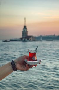 Cropped hand of woman holding drink at beach