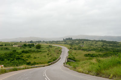 Road amidst green landscape against sky