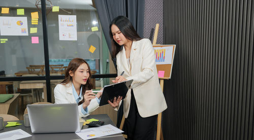 Portrait of smiling woman using digital tablet while standing in office