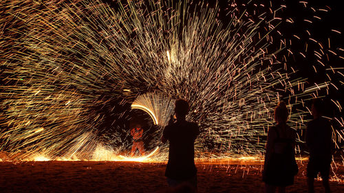 Silhouette people with fire crackers at night