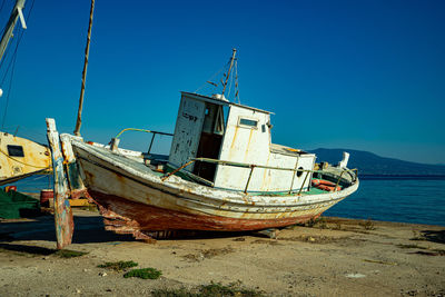 Boat moored on beach against clear blue sky