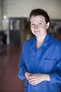 Portrait of confident female electrician standing in factory