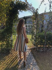 Young woman looking away while standing against plants