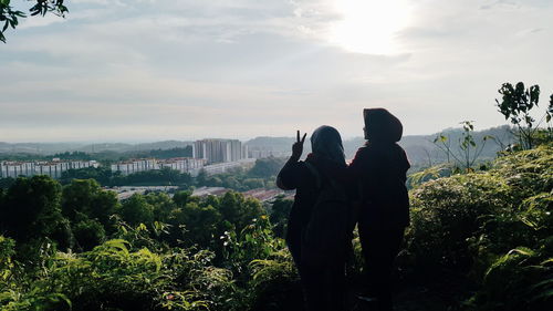 Rear view of people looking at cityscape against sky