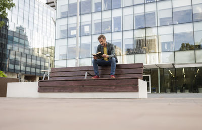 Man sitting on bench and reading book