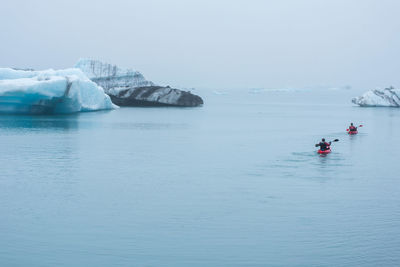 Man paddling in a kayak in the freezing waters of jokulsarlon glacier lagoon between icebergs