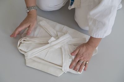 Midsection of woman folding kimono on floor