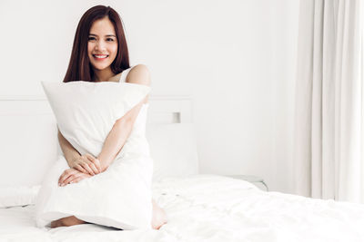 Portrait of a smiling young woman sitting on bed