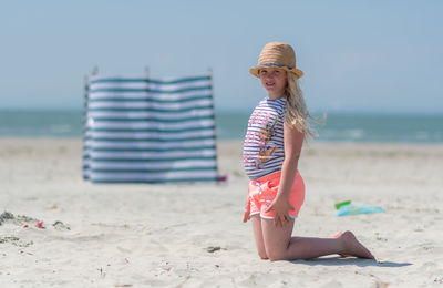 Full length of cute boy on beach against sky