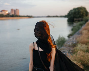 Rear view of woman standing in water against sky